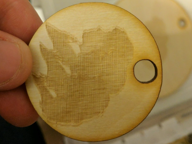 a round wood laser cut and engraved project with a ghosted image engraced on it