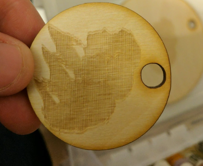 a round wood laser cut and engraved project with a ghosted image engraced on it