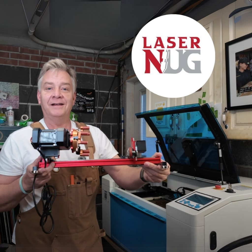 light skinned older man holder a red metal rotary device standing next to a blue and white Thunder Laser cutter machine